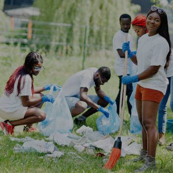 Group of happy african volunteers with garbage bags cleaning area in park. Africa volunteering, charity, people and ecology concept.